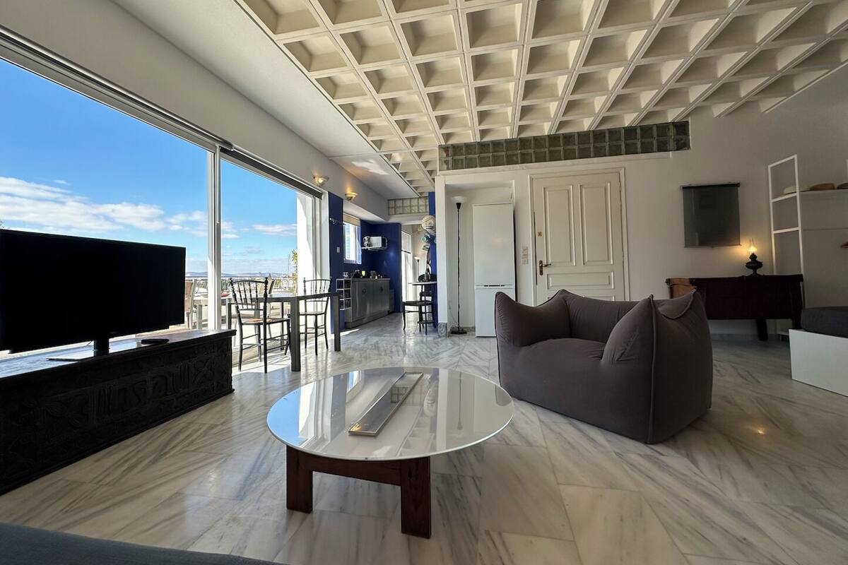 A spacious living area with a large TV, a round coffee table, and a sofa.