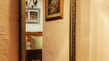 Un escritorio de madera con un espejo grande y ornamentado, una lámpara arriba y un cuadro en la pared.