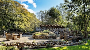 A garden patio with stone walls, a wooden pergola, and outdoor furniture. - Tudor Lodge (Glendalough)