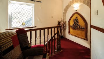 A staircase with a wooden railing, a red carpet, and a wall-mounted light fixture.