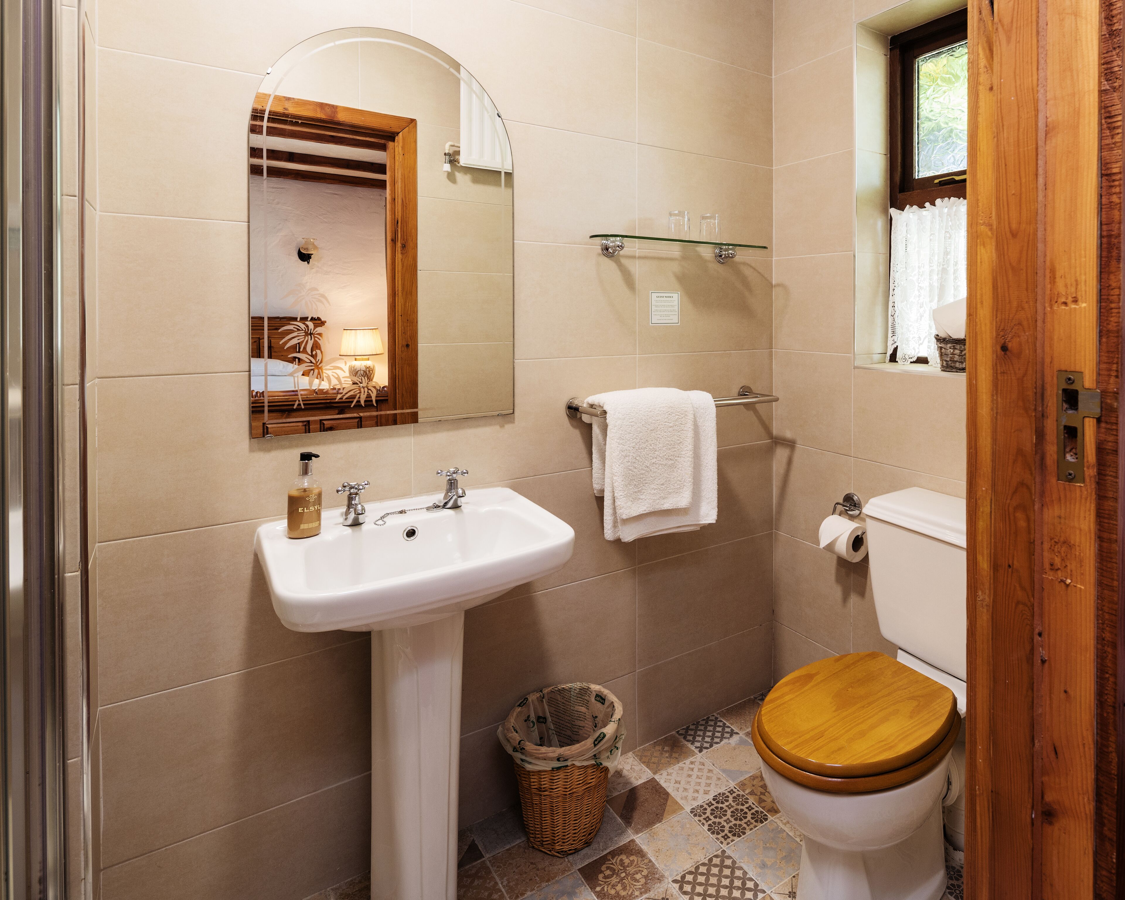 A bathroom with a sink, mirror, toilet, and a window.