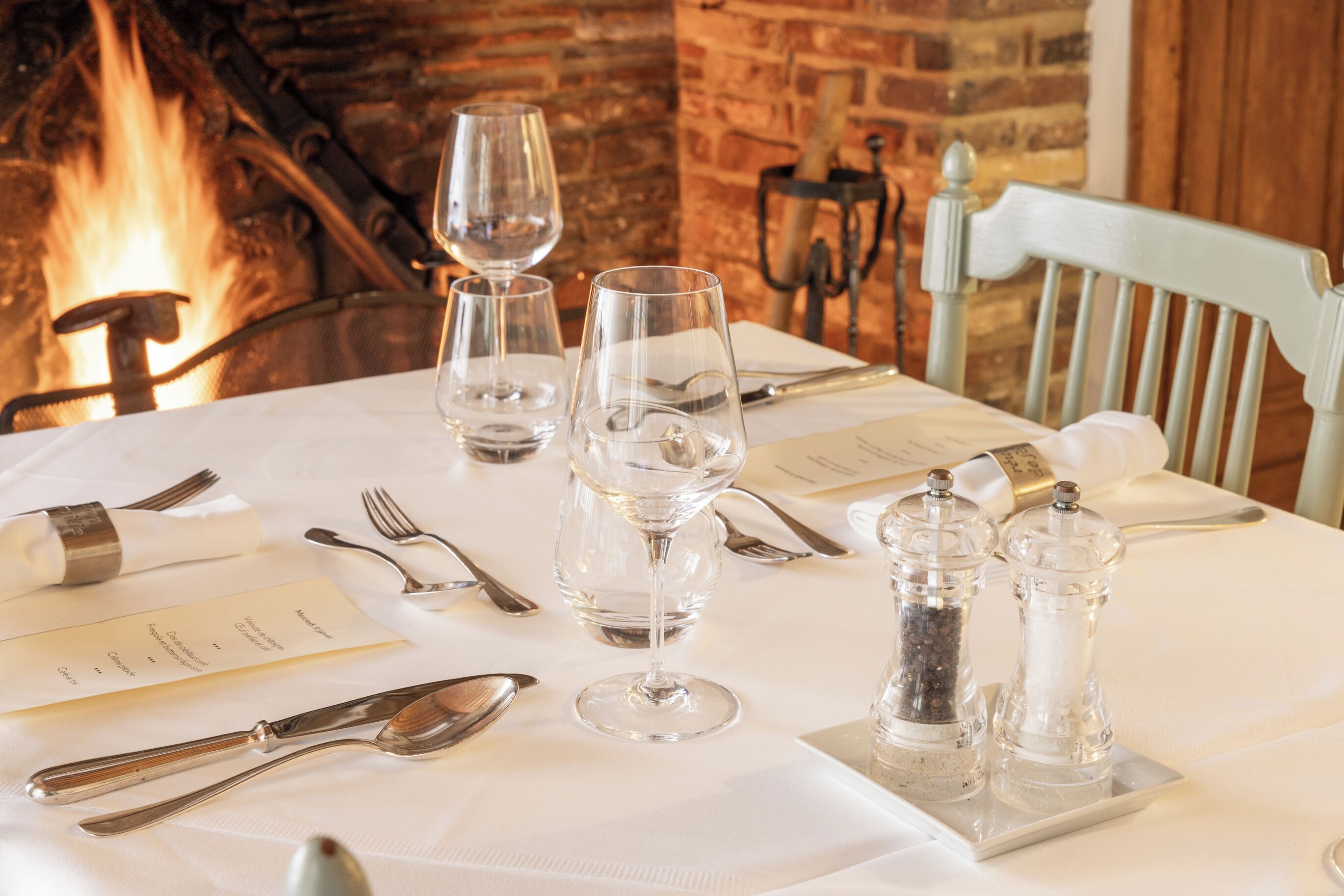 Une table mise pour un repas, avec des verres à vin, des couverts et des salières et poivrières.