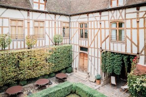 A courtyard with a traditional half-timbered building, a round table, and chairs.