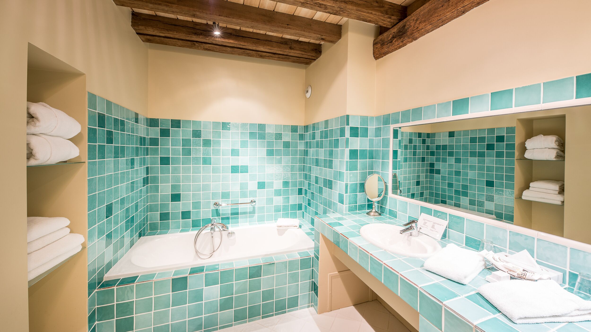 A bathroom with a bathtub, a sink, a mirror, and shelves with towels.