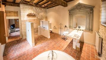 A bathroom with a stone wall, a wooden ceiling, a white sink, and a mirror.