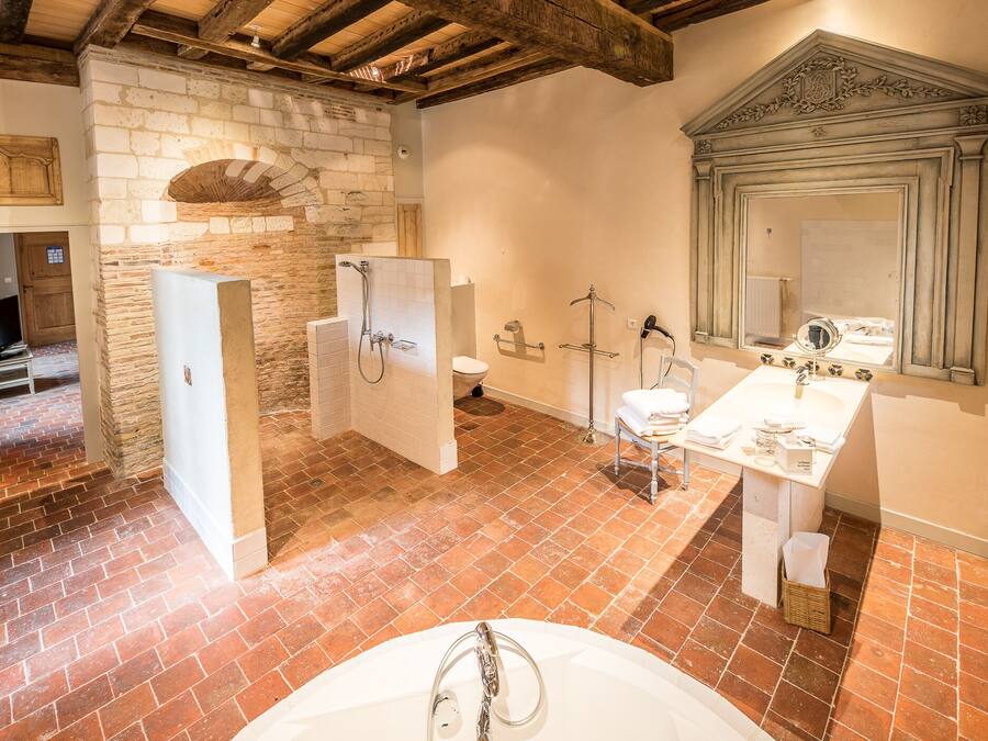 A bathroom with a stone wall, a wooden ceiling, a white sink, and a mirror.