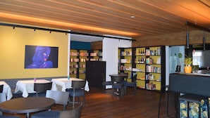 Un interior moderno con techo de madera, mesas, sillas y estanterías.
