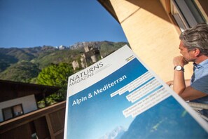 Une personne est en train de lire un magazine intitulé « NATUR’S MAGAZINE », avec en arrière-plan un paysage de montagne.