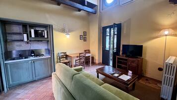 A compact living space with a kitchenette, a sofa, a dining table, and a television.
