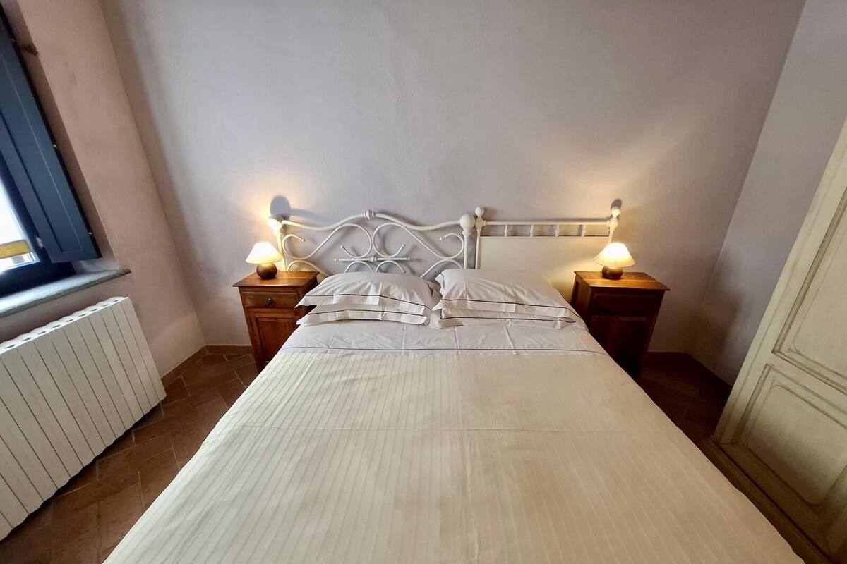A neatly made bed with a white headboard and two bedside tables with lamps.