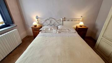 A neatly made bed with a white headboard and two bedside tables with lamps.