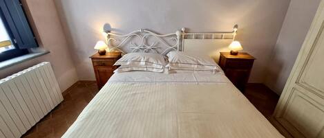 A neatly made bed with a white headboard and two bedside tables with lamps.
