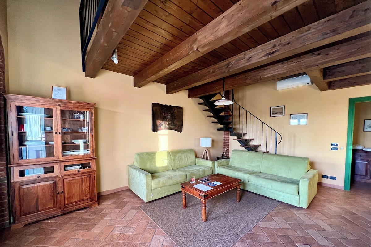 A living room with a wooden cabinet, a green sofa, a wooden coffee table, and a staircase.