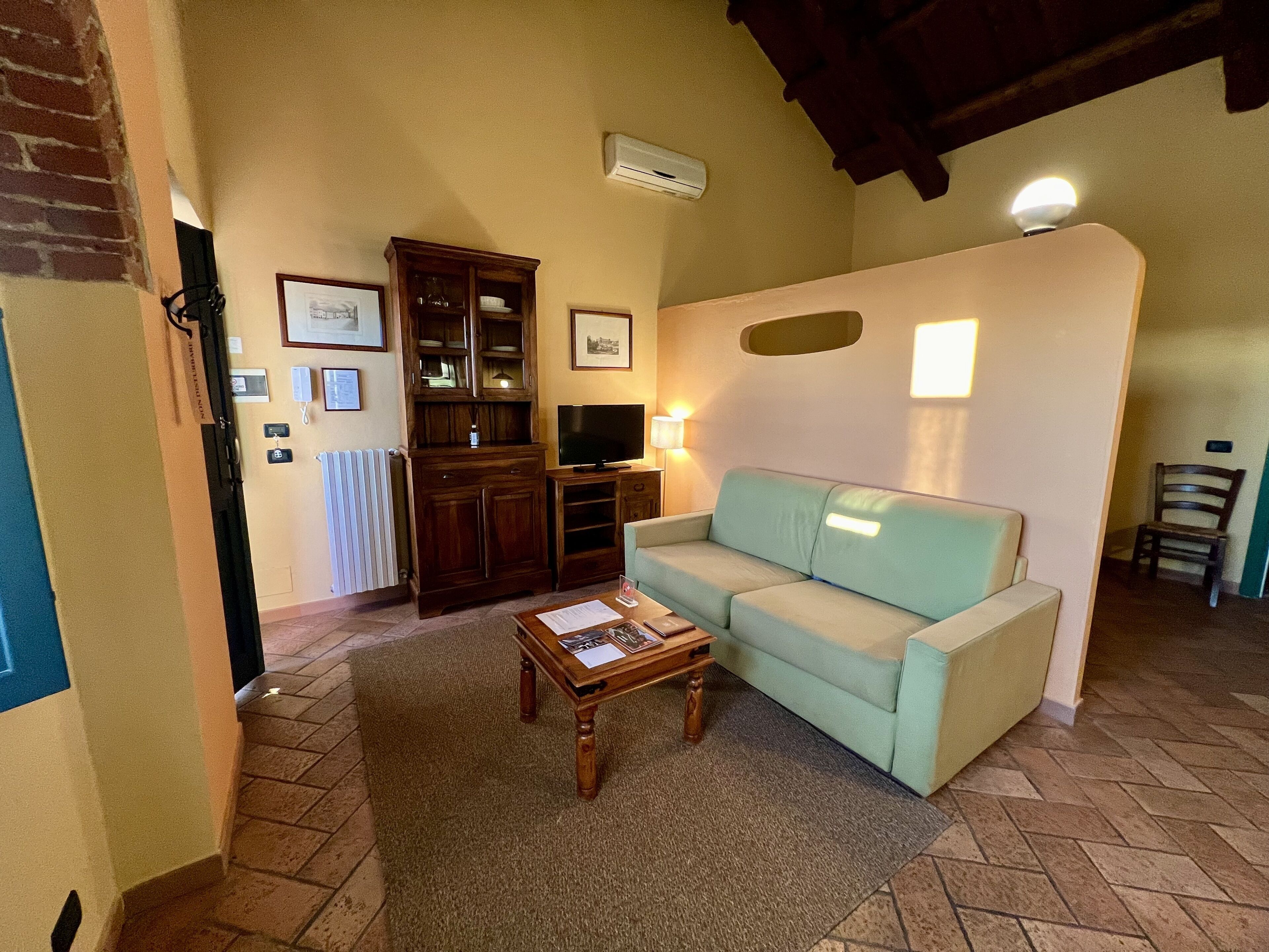 Una sala de estar acogedora con un sofá azul claro, un mueble de entretenimiento de madera y piso de baldosas.