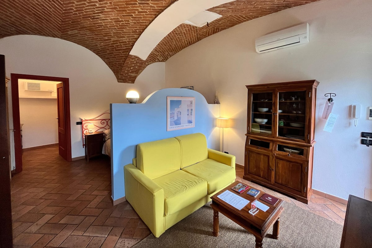 A living room with a yellow sofa, a wooden cabinet, and a tiled floor.