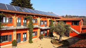 A building with multiple balconies, solar panels on the roof, and a courtyard with a tree and potted plants.