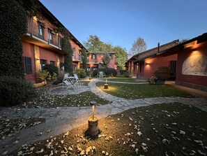 Un patio con senderos de piedra, mobiliario exterior y una chimenea central.