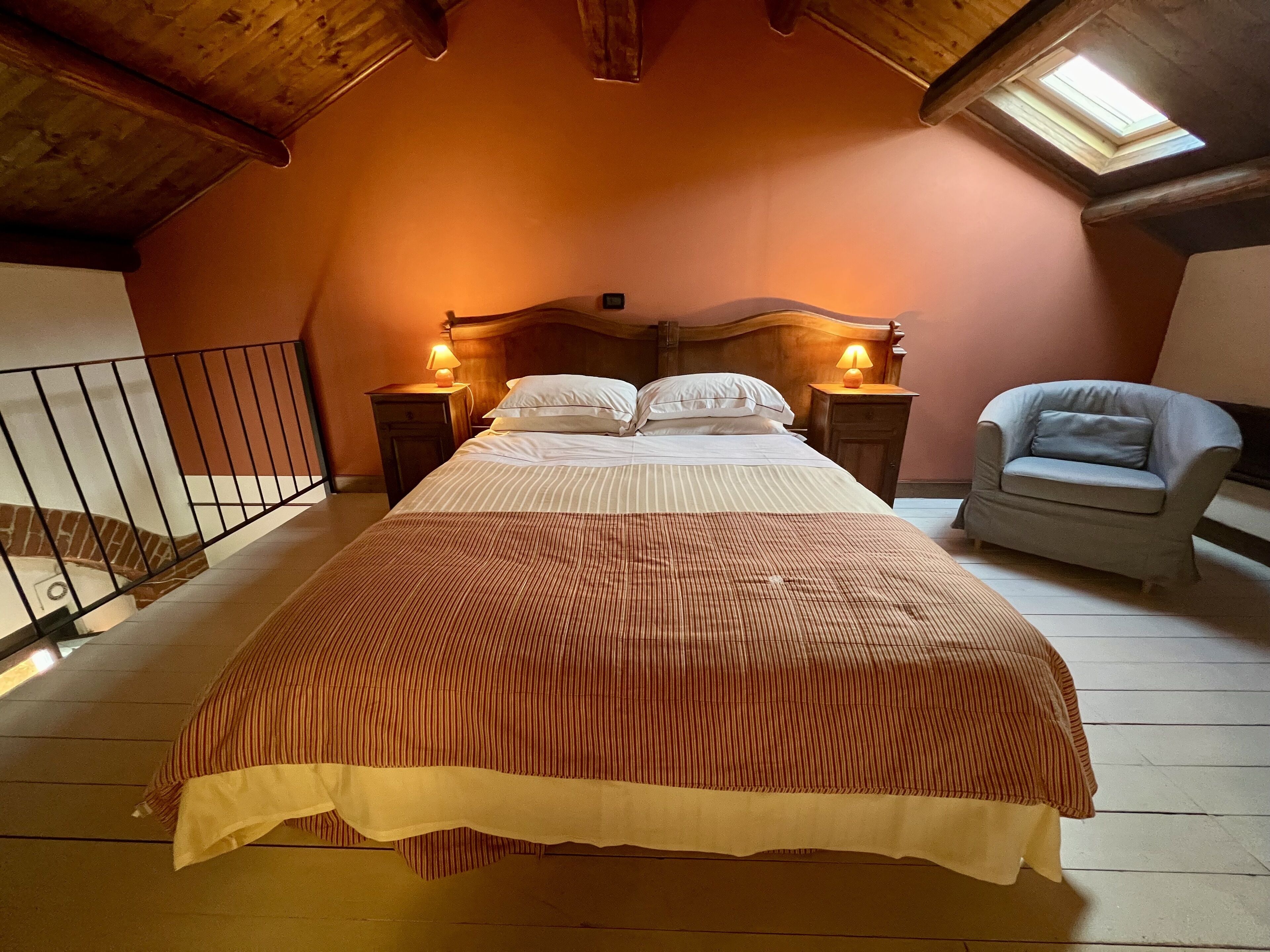 Une chambre à coucher avec un lit, deux tables de chevet avec des lampes, une chaise et une lucarne.