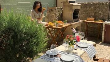 Un espacio de comedor al aire libre con pared de piedra, antena parabólica y horno para pizzas.