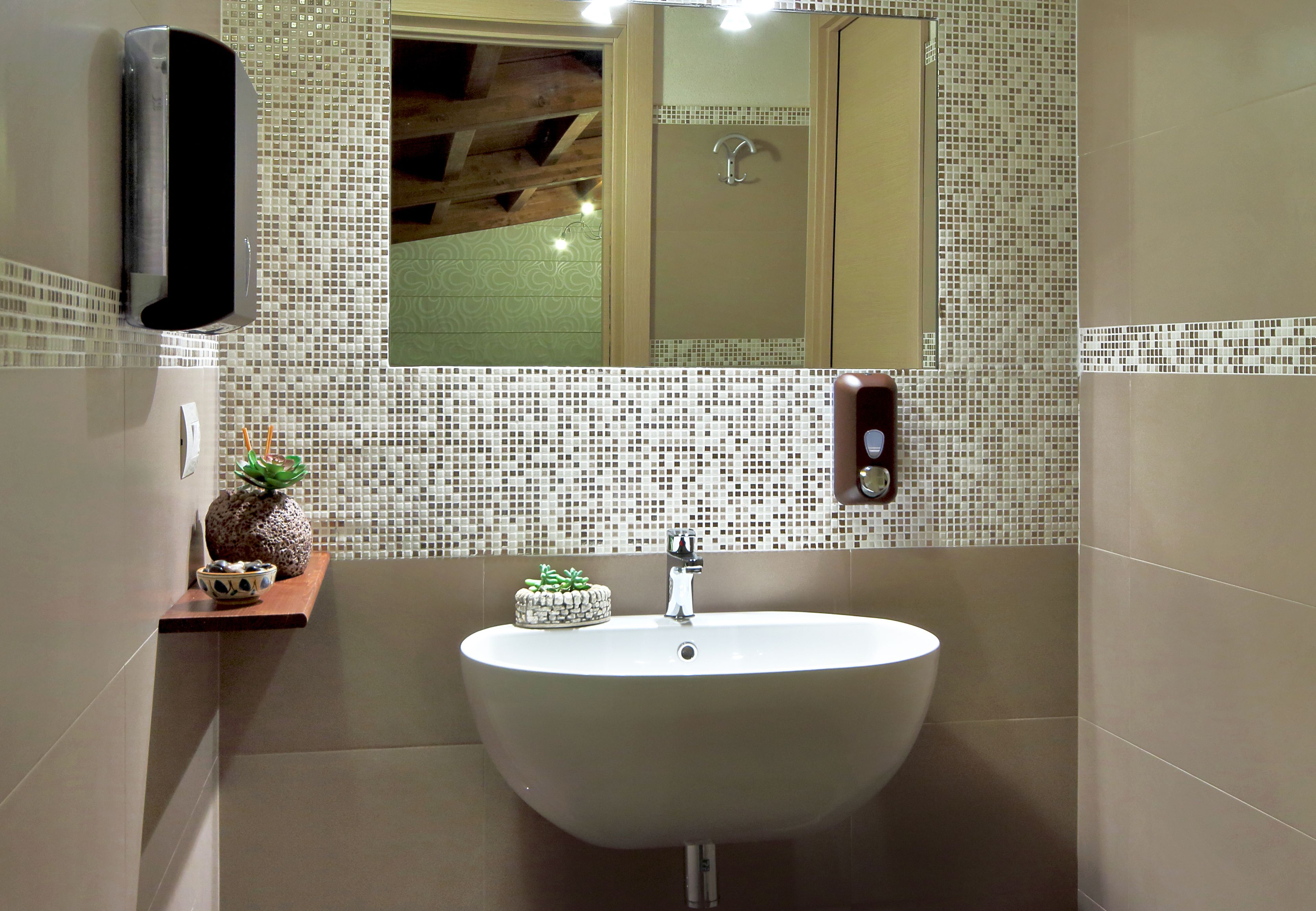 Ein Badezimmer mit einem weißen Waschbecken, einem Spiegel und einem kleinen Regal mit Dekorationen.
