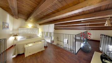 Une chambre avec un plafond en bois, un lit avec une tête de lit, une table de chevet, une commode, une fenêtre avec des rideaux, un balcon avec une balustrade et un vase rempli de fleurs.