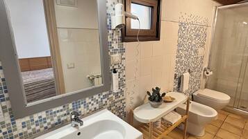 Une salle de bain avec un grand lavabo, deux toilettes, un miroir et une douche.