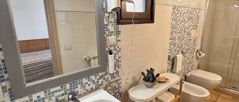 A bathroom with a large sink, two toilets, a mirror, and a shower.