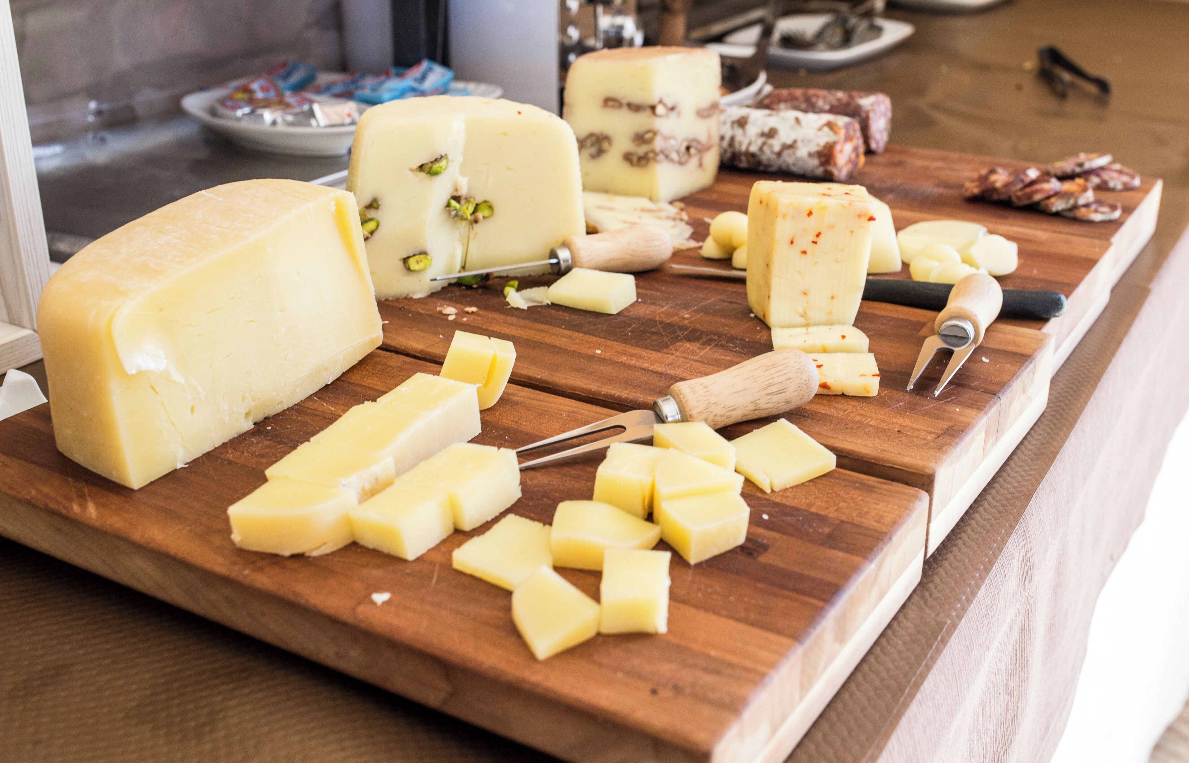 A variety of cheeses and meats on a wooden cutting board.