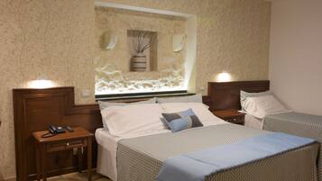 A hotel room with two beds, a small bedside table with a phone, and a wall-mounted vase.