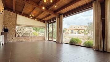 A spacious room with a high ceiling, stone wall, and large windows.
