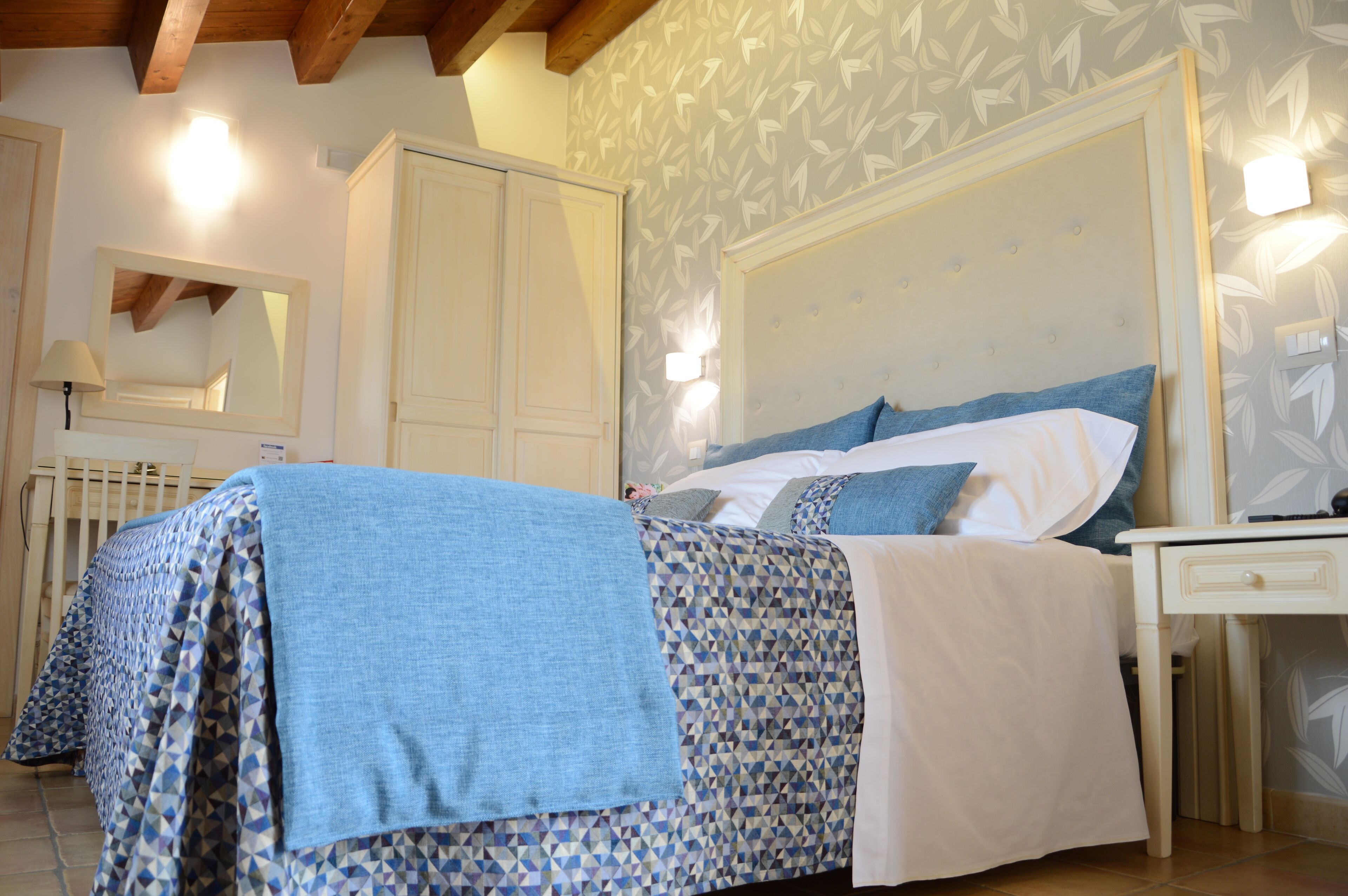 A bedroom with a bed, a nightstand, a dresser, and a mirror.