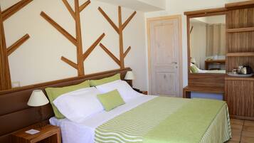 Una cama bien hecha con colcha a rayas, una mesita de noche con lámpara y un cabecero de madera con diseño de árbol.