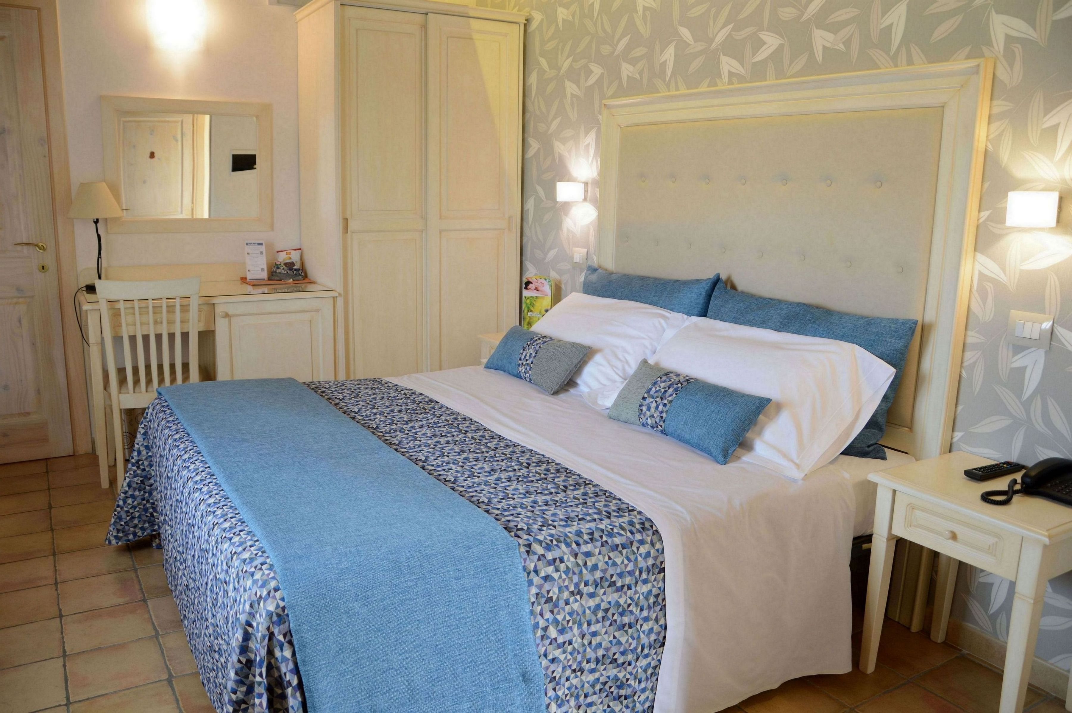 A neatly arranged bedroom with a large bed, bedside tables, a desk, and a wardrobe.