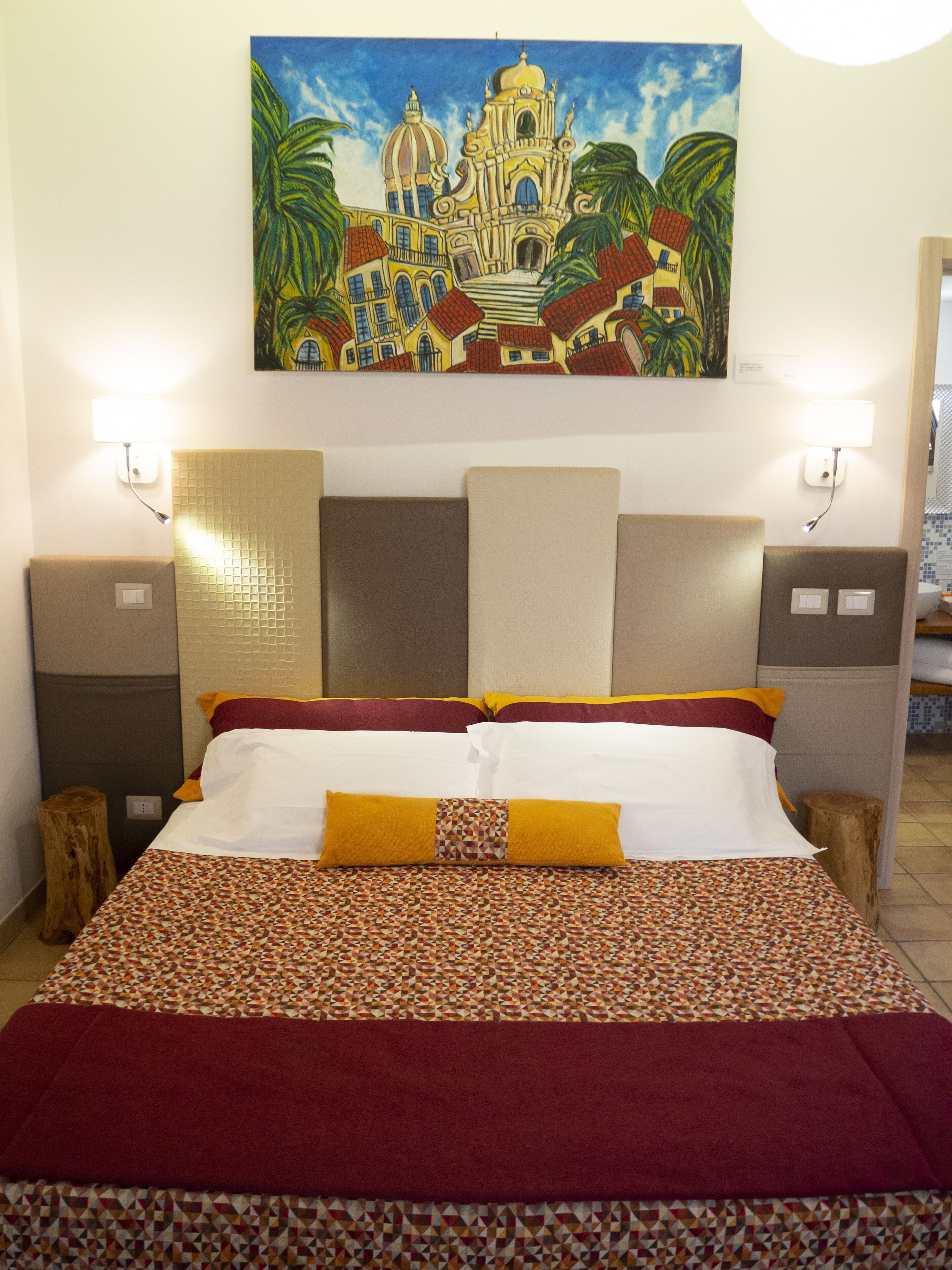 Ein Hotelzimmer mit einem Bett, Kissen, einem Kopfteil, einem Nachttisch und einem Bild an der Wand.