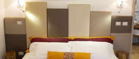 Ein Hotelzimmer mit einem Bett, Kissen, einem Kopfteil, einem Nachttisch und einem Bild an der Wand.