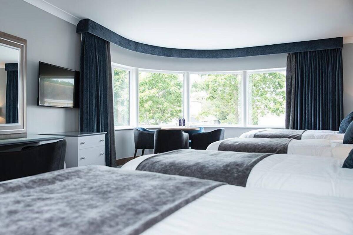 A hotel room with two beds, a desk, and a chair.