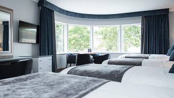 A hotel room with two beds, a desk, and a chair.