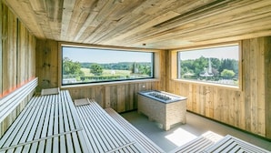 A wooden interior with large windows, a sauna, and a stone fireplace. - Romantik Hotel Schwanefeld (Meerane)