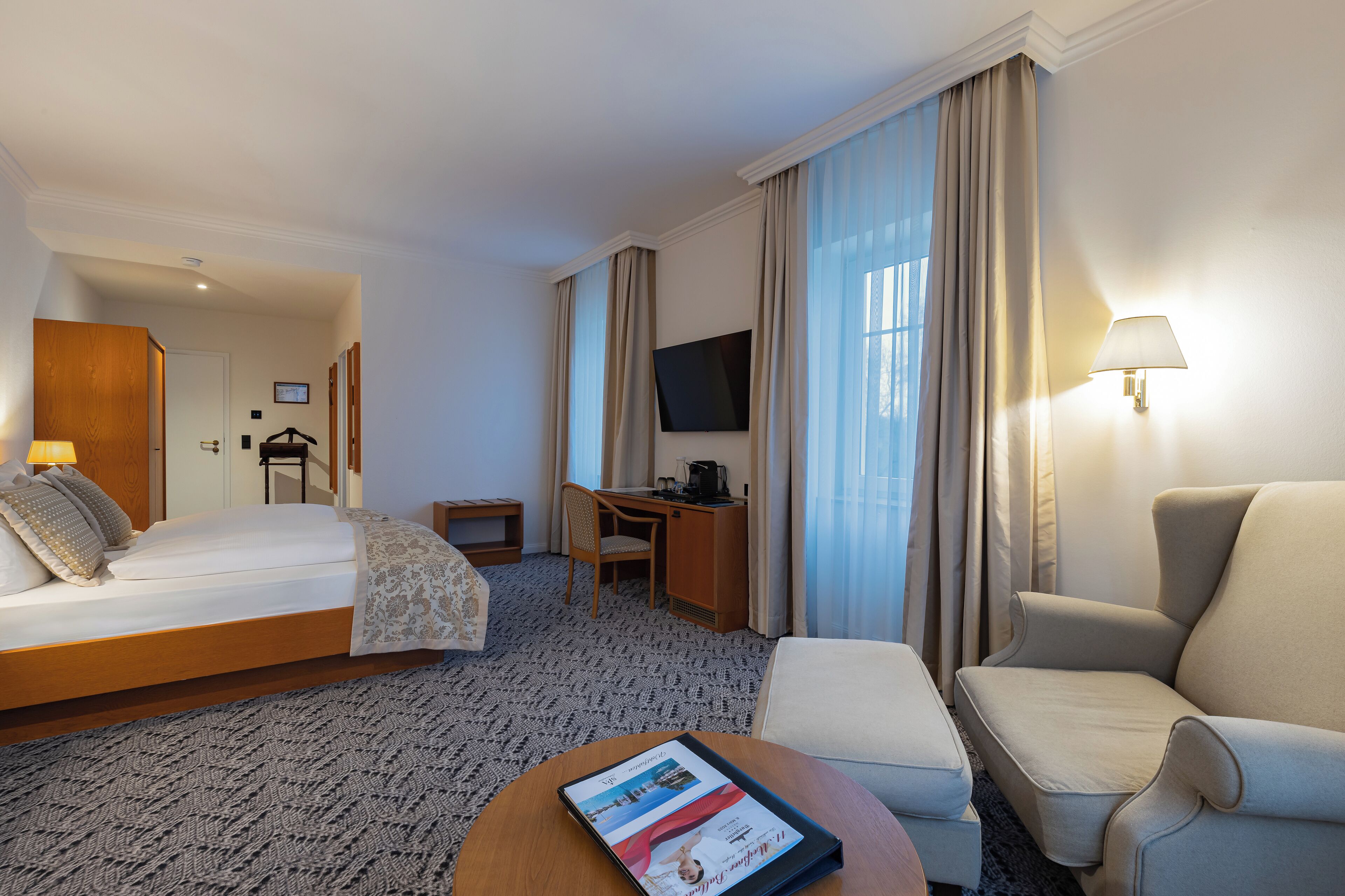 Una habitación de hotel con una cama grande, un escritorio, un televisor y una silla.