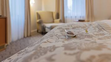 A hotel room with a bed, a chair, and a window with curtains.