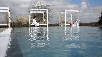 A pool area with three white structures, each with a bench and a person sitting.