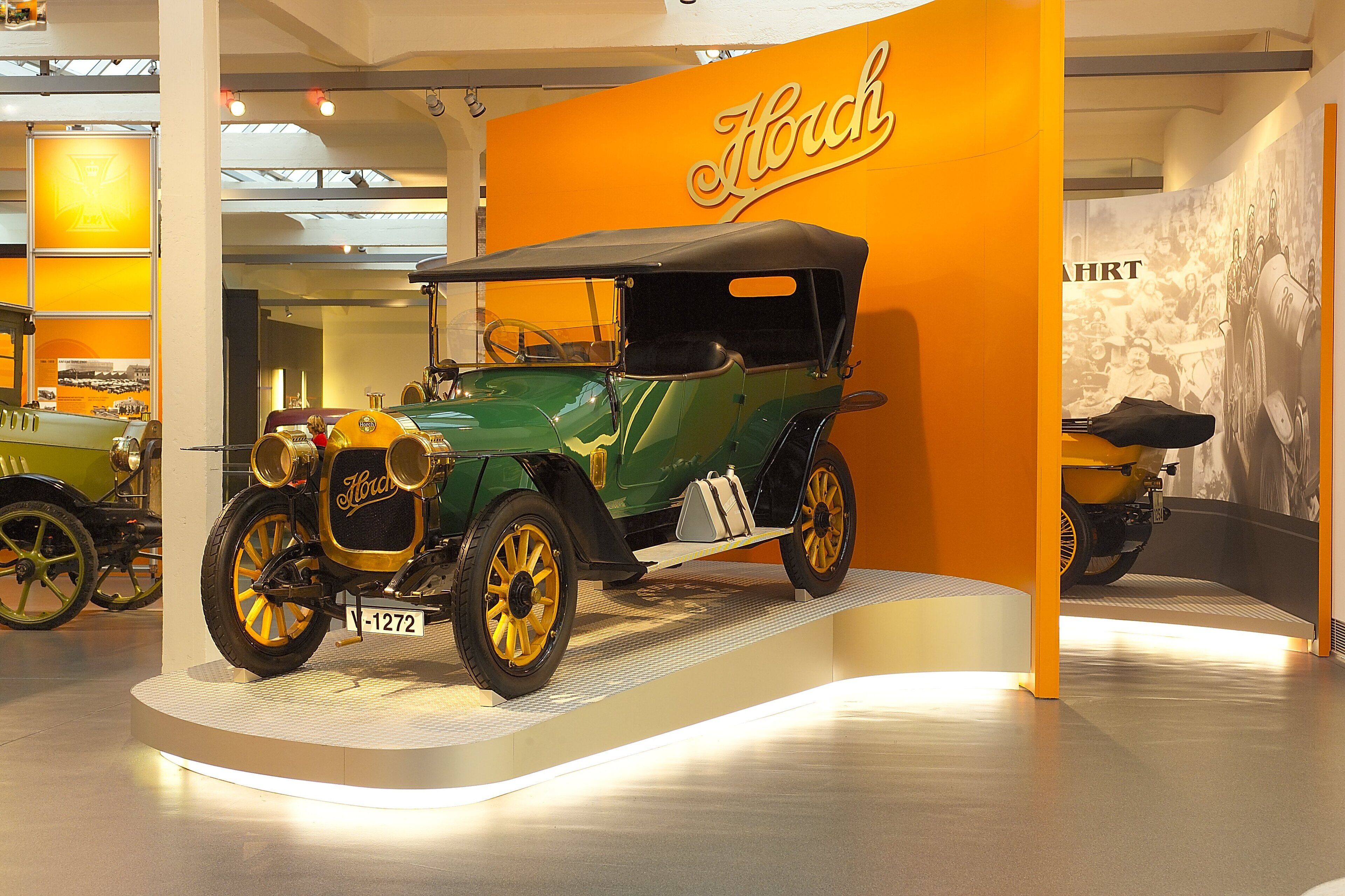 Un coche antiguo exhibido con un letrero que dice "Horch" al fondo.