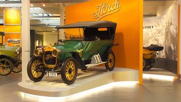 Un coche antiguo exhibido con un letrero que dice "Horch" al fondo.