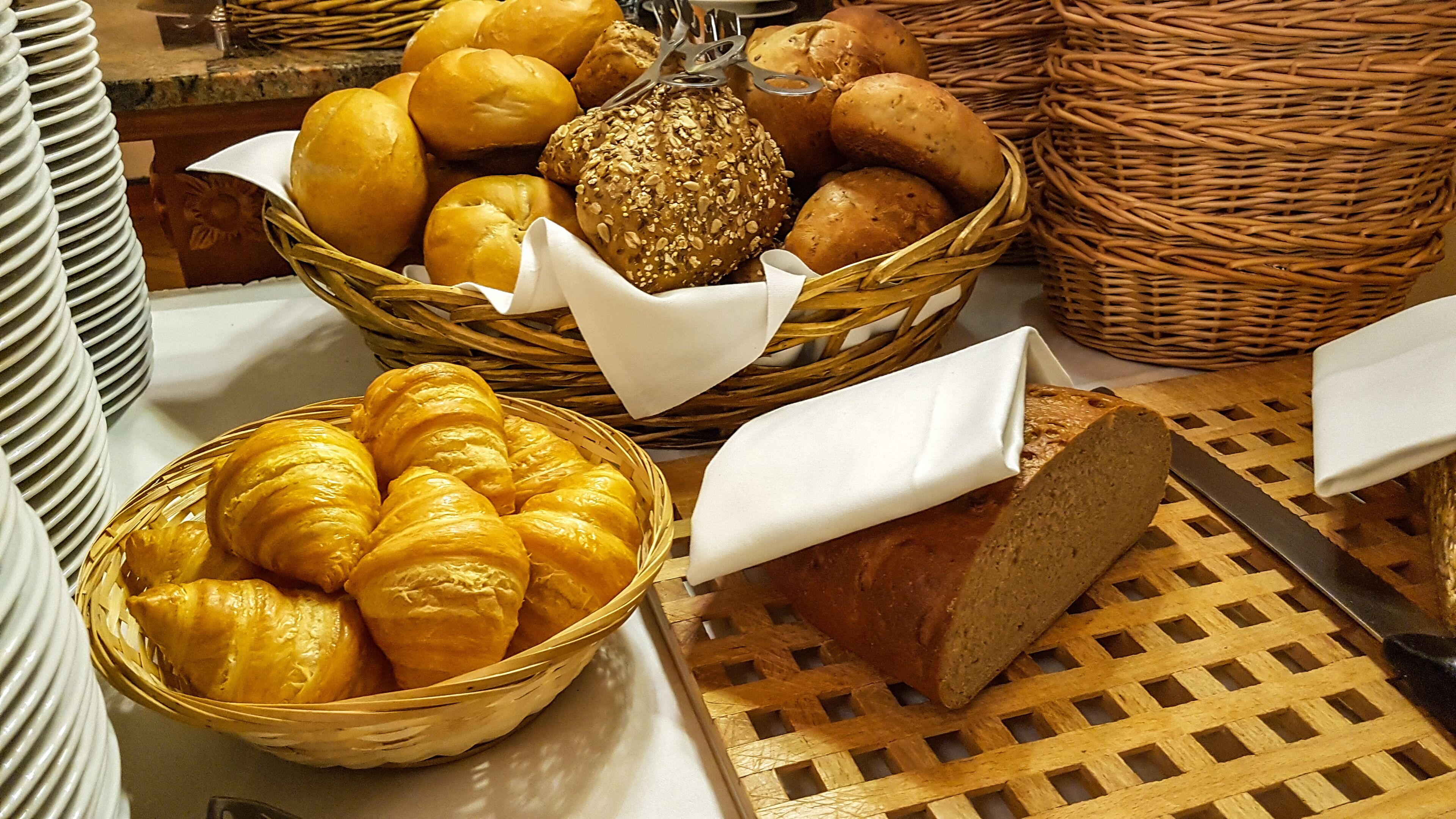Variedad de panes y pasteles en cestas, un pan sobre tabla de cortar y un cuchillo.