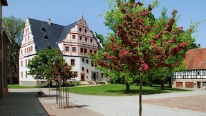 A traditional half-timbered building with a steeply pitched roof and a prominent tower. - Romantik Hotel Schwanefeld (Meerane)
