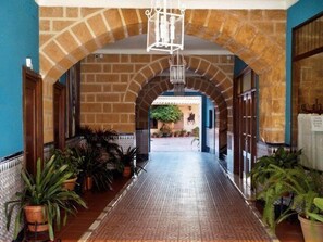 Un couloir avec un sol carrelé, des murs en briques et des plantes en pot.
