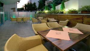 Un espacio al aire libre con patio, muebles de mimbre, una mesa de madera y plantas en macetas.