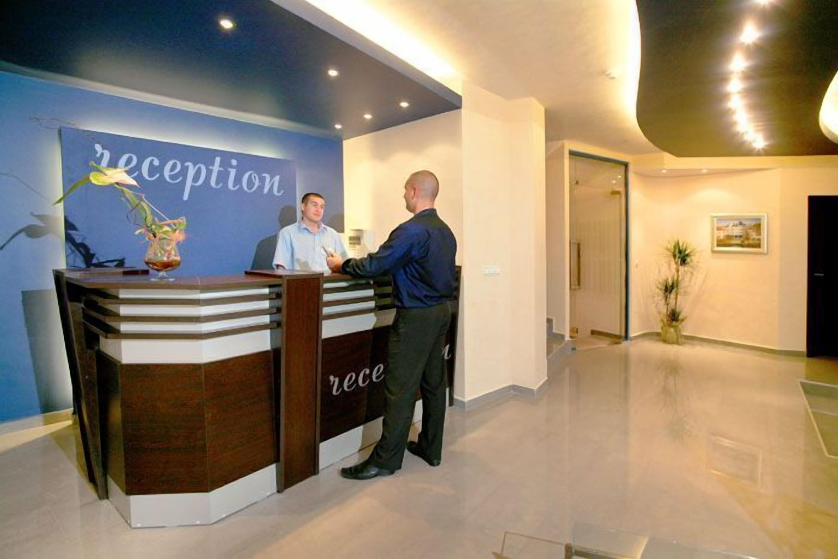 A reception desk with a sign that reads "reception" and a man standing next to it.