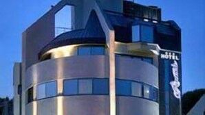 Un hotel moderno con fachada curva, múltiples ventanas y una escalera que conduce a la entrada.