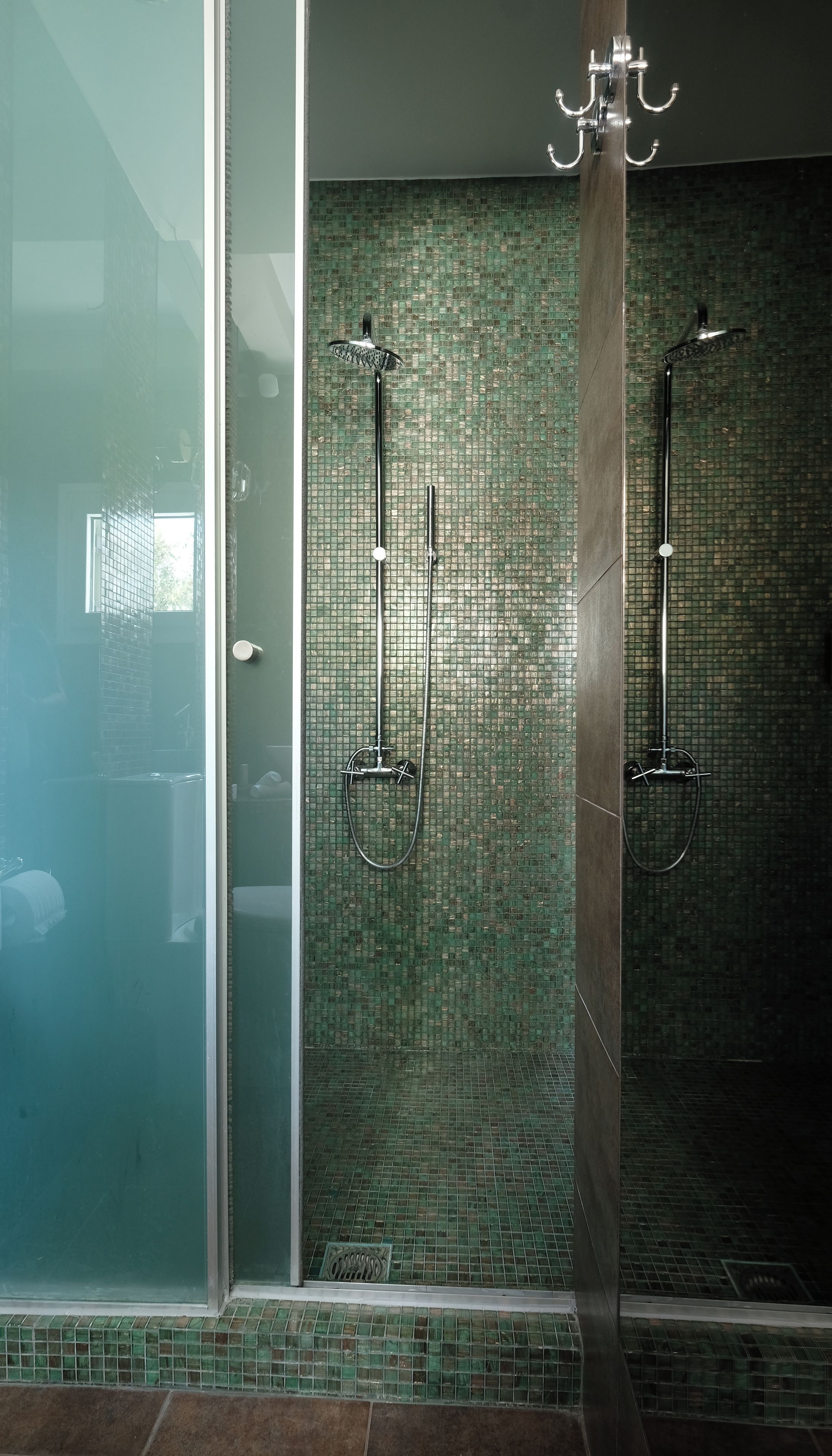 A shower area with a glass door and a tiled wall.